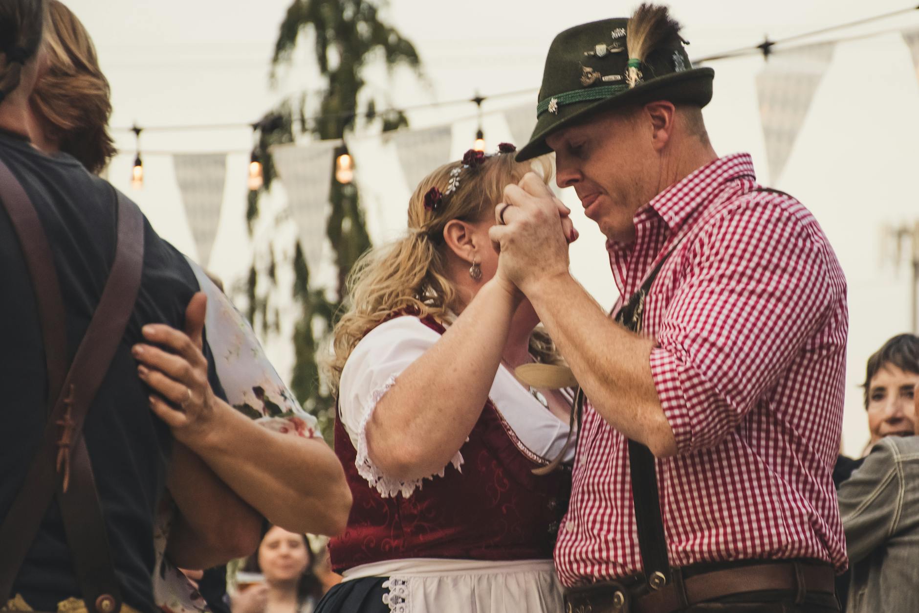 Couple in traditional Bavarian Tracht – lederhosen and dirndl – walking toward the Oktoberfest entrance