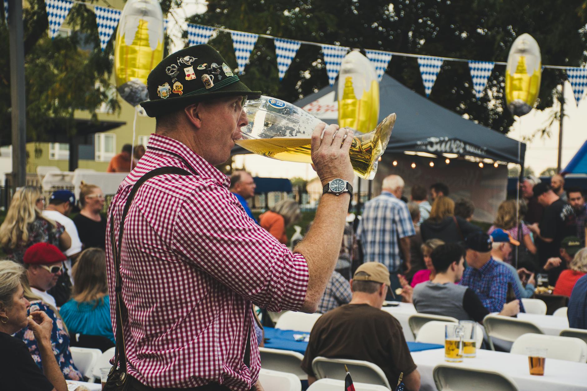 Server carrying ten Maß beer steins through a crowded Oktoberfest tent