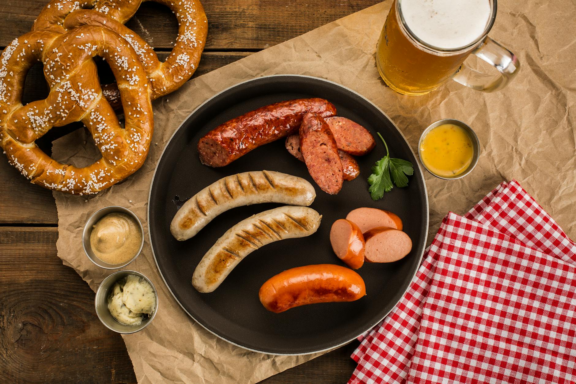 Half roast chicken (Hendl) and a giant pretzel on a wooden Oktoberfest table next to a Maß of beer