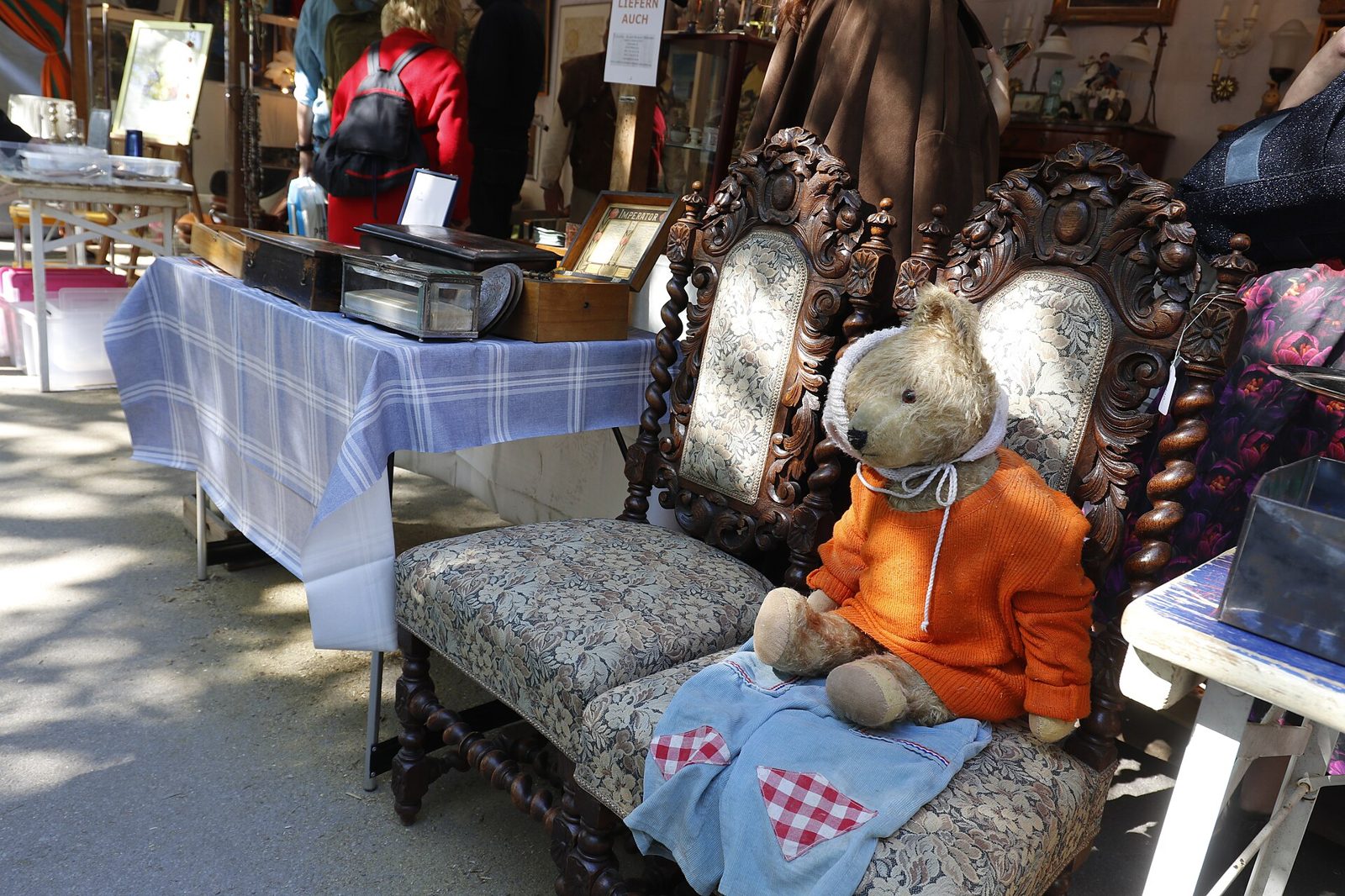 Auer Dult: Munich's Traditional Fairs and Markets 2 Two carved antique chairs, one holding a teddy bear in an orange jumper, at an Auer Dult market stall