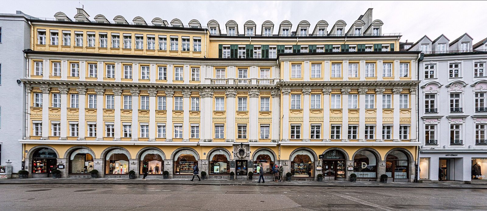 Michelin-Star and Fine Dining in Munich 1 The long yellow and white façade of the Dallmayr building on Dienerstraße, with arched shop windows at street level