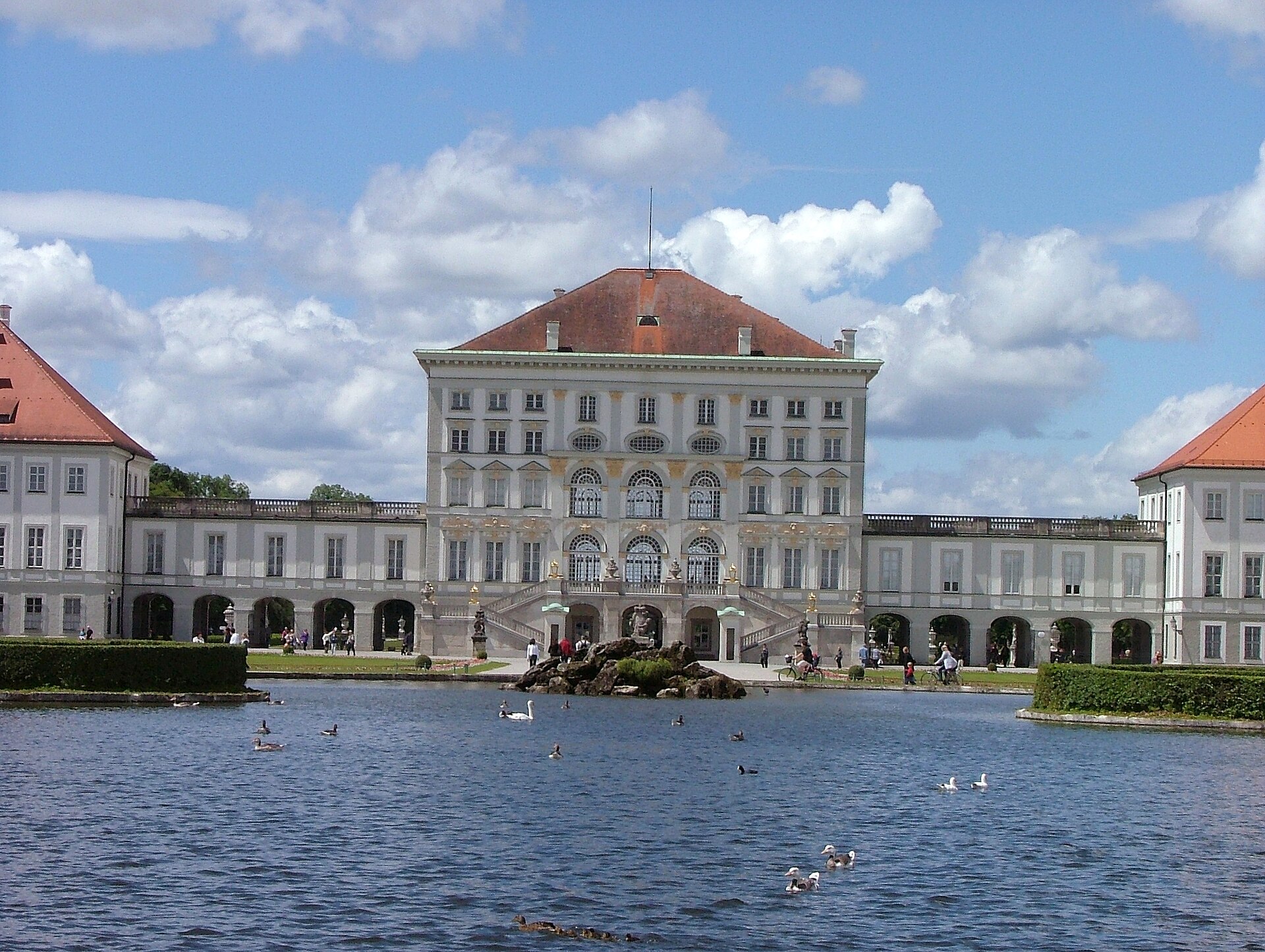 Nymphenburg Palace Munich: Complete Visitor Guide (2026) 1 Nymphenburg Palace’s central pavilion rises above arched galleries and twin staircases, with waterbirds swimming across the foreground basin.