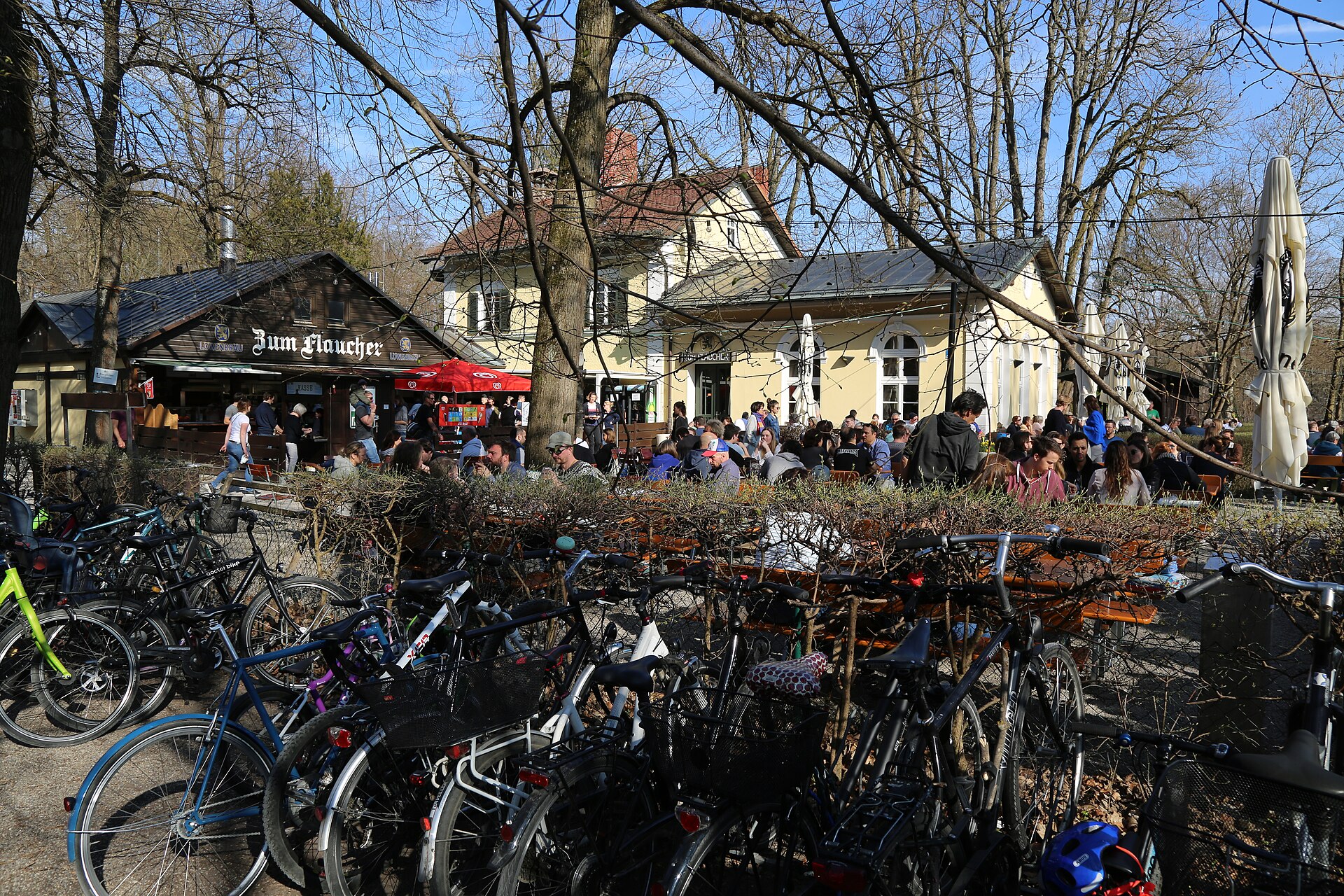 Sendling and Westpark: Munich's Green South 3 Parked bicycles line the busy Zum Flaucher beer garden in Munich, with visitors sitting outside the yellow inn.