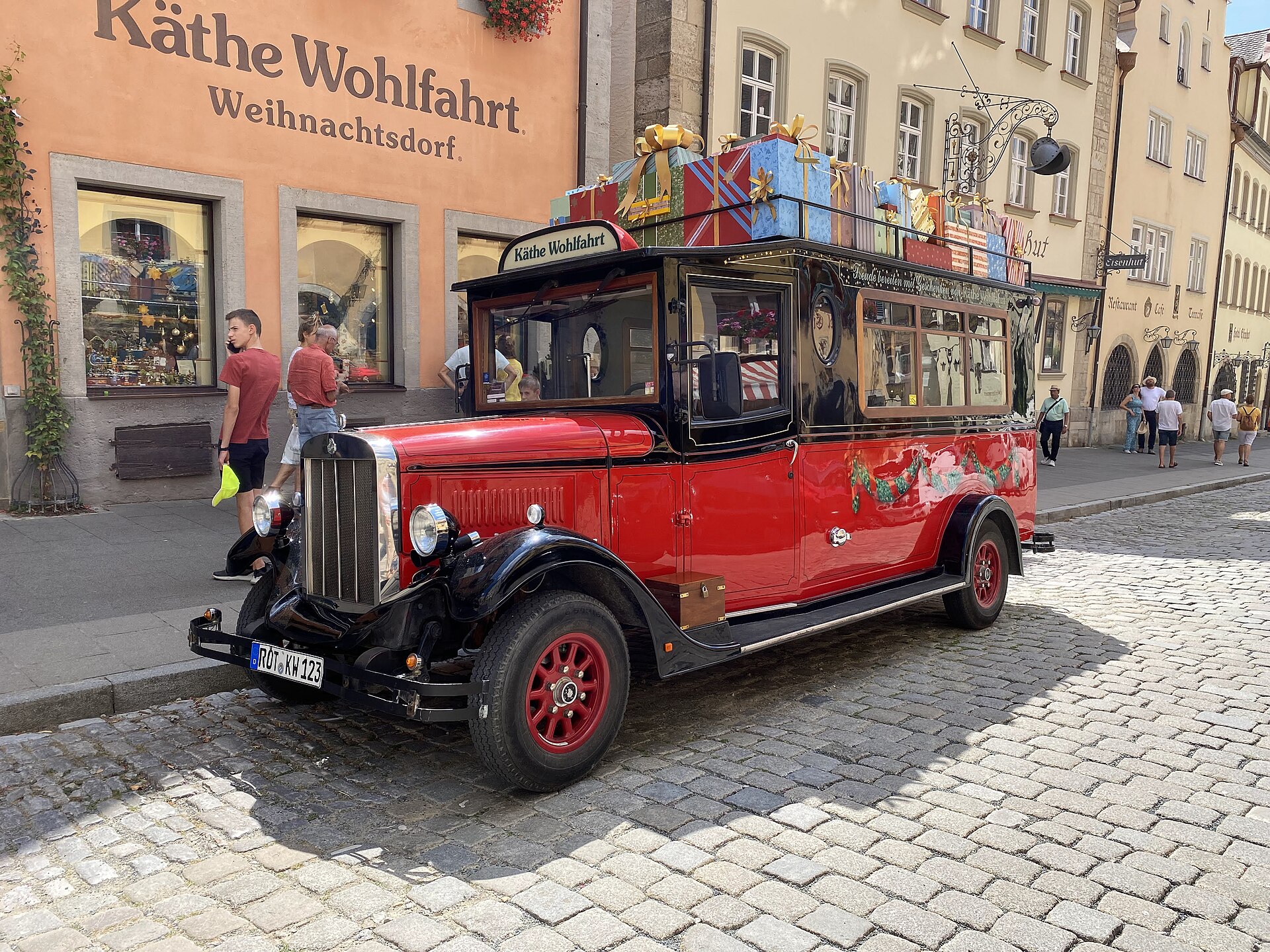 Rothenburg ob der Tauber from Munich: Complete Day Trip Guide 2 A red gift-laden vehicle stands outside Käthe Wohlfahrt’s Weihnachtsdorf shop on a cobbled Rothenburg street.