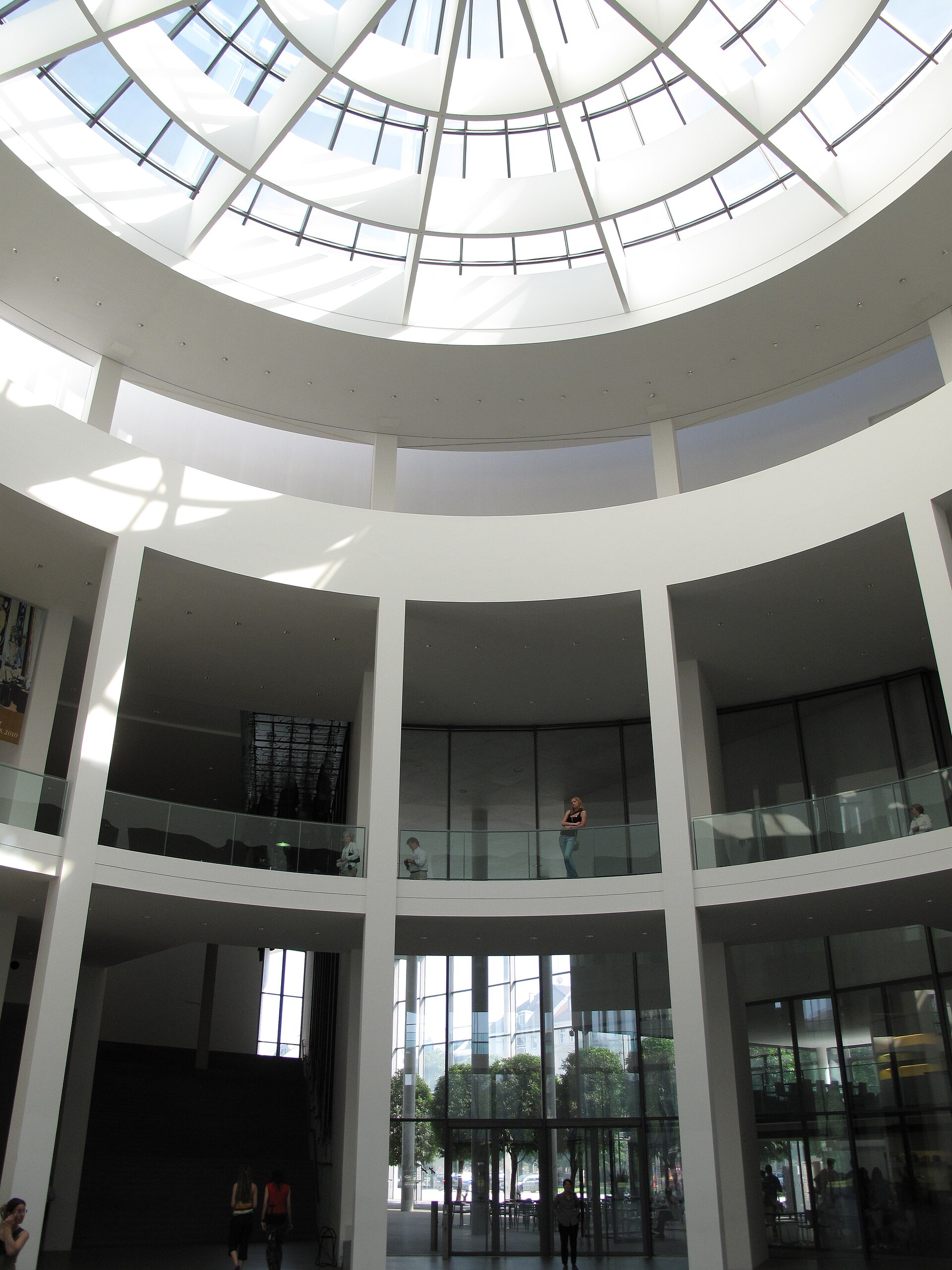 Munich Kunstareal: Complete Guide to the Art Quarter 2 Visitors stand on two levels beneath the glass dome of the Pinakothek der Moderne rotunda in Munich.